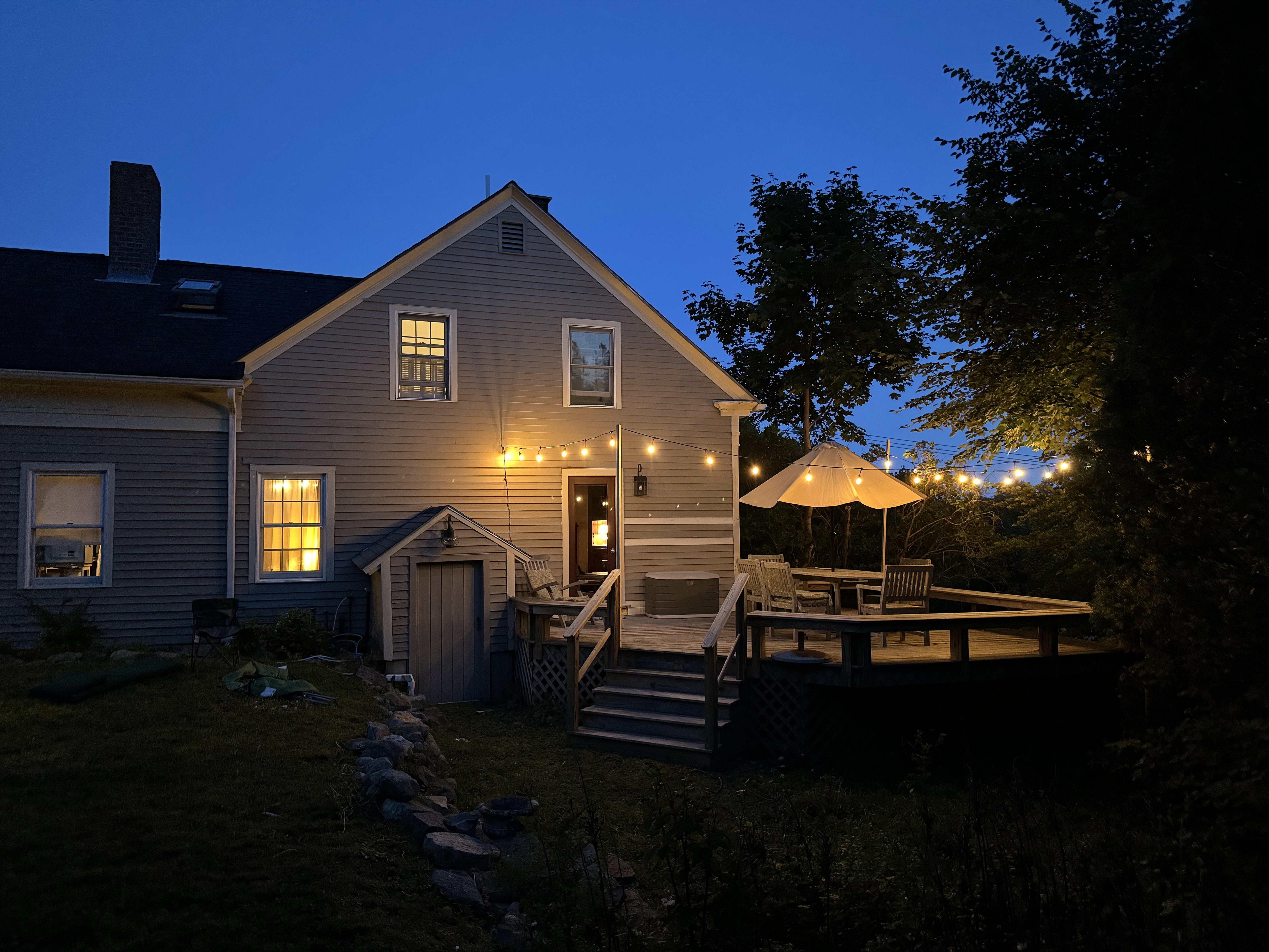 The Warren at dusk — string lights on the deck of an 1855 coastal farmhouse in Southwest Harbor, Maine